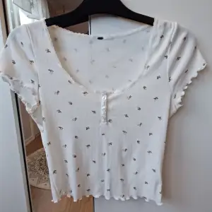 Säljer en söt vit ribbad topp med små blommor och knappar framtill 💕 Den är lite genomskinlig, se sista bild! 💓(Det står ej storlek, men skulle gissa på M)