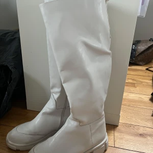 Vita höga stövlar - Snygga vita stövlar i skinn med hög skaft. Perfekta för att ge en stilren look. Passar bra till både kjol och byxor.
