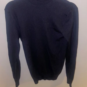 Svarttröja från J. Lindeberg - Säljer en stilren mörkblå tröja från J. Lindeberg. Tröjan är långärmad och har en diskret broderad logga på bröstet. Perfekt för en klassisk och tidlös look.