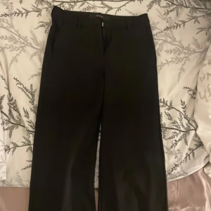 Svarta kostymbyxor från Vero Moda - Snygga svarta kostymbyxor från Vero Moda med dragkedja och knappstängning. Perfekta för en stilren look.