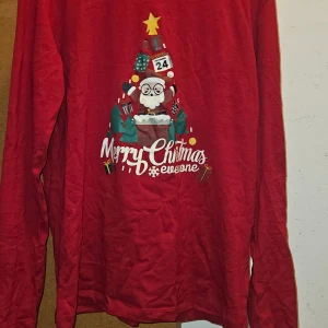 Röd jultröja med tryck - Säljer en röd långärmad jultröja med ett festligt tryck och text  'Merry Christmas everyone'. 