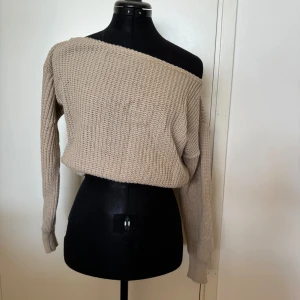 Beige stickad offshoulder tröja från Boohoo - Säljer en superfin beige stickad tröja från Boohoo. Den har en snygg offshoulder-design som ger en avslappnad och trendig look. Perfekt för höst och vinter, och den är riktigt mysig att ha på sig. Tröjan har långa ärmar och en normal passform. Perfekt för att matcha med jeans eller kjol för en chic outfit!