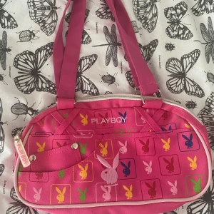 2000s playboy väska 💗 - Har haft väskan jättelänge men bara använt den fåtal gånger! Den är i bra skick, blixtlåsen bakom väskan har gått sönder lite (alltså plasten, man kan se på bild 3) Skriv gärna om du har frågor angående väskan eller vill ge ditt pris 💕