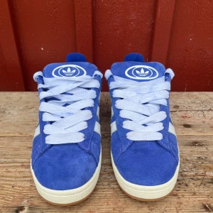 Adidas campus 00 - nästintill nya addidas campus skor, Max använda 10 gånger och köptes för 1000kr. Färgen är blå och det tillkommer vita och matchande blå skosnören! Inga defekter så skulle säga att de är i nyskick!