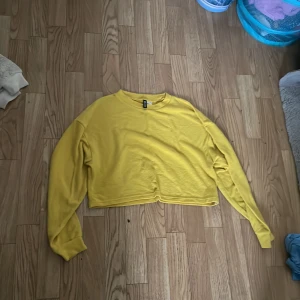 Gul croppad tröja från Divided - Säljer en superfin gul croppad tröja från Divided. Den är perfekt för både vår och sommar med sin ljusa färg och bekväma passform. Tröjan är långärmad och gjord av mjukt material som känns skönt mot huden. Passar perfekt till ett par höga jeans eller shorts! 🌼