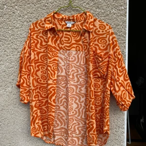 Orange skjorta - Jättehärlig orange skjorta i flowigt material och fint mönster. Inte använd så mycket alls så är i jättefint skick.