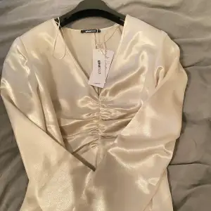 Säljer en elegant champagnefärgad blus från Gina Tricot. Den har en v-ringad design med snygg rynkdetalj framtill. Perfekt för festliga tillfällen! Storlek 42 men passar med mig som bär S,36,38 på tröjor❤️