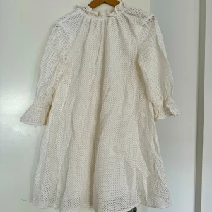 Vit klänning från Carin Wester - Säljer en  vit klänning från Carin Wester i storlek 34. Den har ett broderat mönster och trekvartsärmar med volangdetaljer. Klänningen är i nyskick (använd en gång) och har en luftig passform. ej steamad/struken på bilderna.