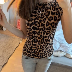 Leopardmönstrad ärmlös topp - Säljer en snygg leopardmönstrad ärmlös topp. Perfekt för att ge din outfit en vild touch. Toppen har en tight passform och är gjord i ett mjukt material som känns skönt mot huden, helt slutsåld
