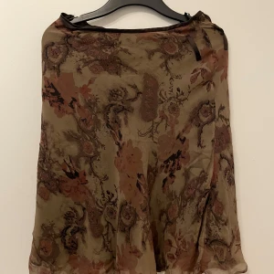 Blommig kjol i bruna toner - Säljer en elegant blommig kjol i olika bruna nyanser. Kjolen har en lös passform och är tillverkad i ett lätt och luftigt material. Perfekt för en stilfull look.