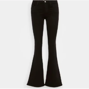 Svarta bootcut jeans - Snygga svarta bootcut jeans med låg midja. Perfekta för en trendig look med en tight passform upptill och utsvängda ben. Klassisk design med knappar och dragkedja framtill.
