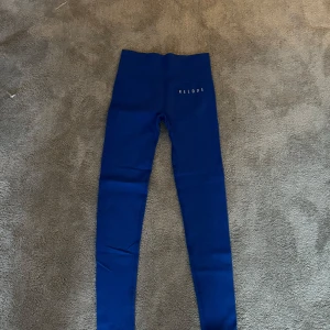 Blå leggings från Relode - Snygga blå leggings från Relode med hög midja. Perfekta för träning eller en avslappnad dag. De är stretchiga och bekväma, vilket gör dem till ett utmärkt val för olika aktiviteter.