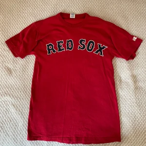 Röd Red Sox t-shirt från Russell Athletic - Säljer en Red Sox tshirt i storlek S. Köptes på Beyond Retro. Har ett hål i midjan på vänster sida (se bild) därav priset. Tvättas och stryks såklart innan frakt! (köparen står för frakten!)
