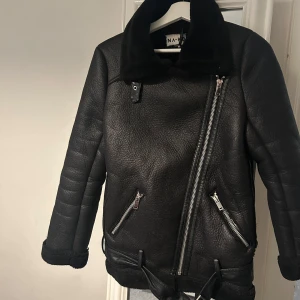 Svart skinnjacka med fuskpäls - Snygg svart skinnjacka från NA-KD med fuskpäls på kragen. Jackan har en asymmetrisk dragkedja och två snedställda fickor med dragkedjor. Perfekt för kyligare dagar med sin stilrena design och varma material. Funkar till vår som till höst. 