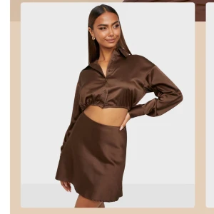 Brunt set från Bianca x Nelly - Snygg brunt set från Bianca Ingrosso x Nelly i ett elegant och glansigt material. Kjolen har en kort längd och en stilren design som passar perfekt för olika tillfällen. Matcha med en topp för en komplett look 🤎