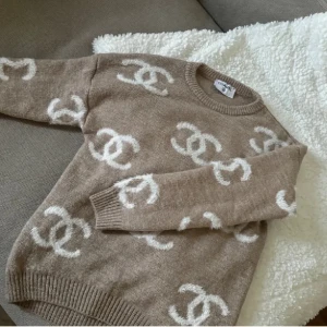 Beige stickad tröja - Säljer en snygg beige stickad tröja från med det ikoniska vita logotypmönstret. Tröjan har långa ärmar och ribbade kanter vid hals, ärmslut och nederkant. Perfekt för en stilren och lyxig look. Storlek S men passar XS också bra bara lite lösare 