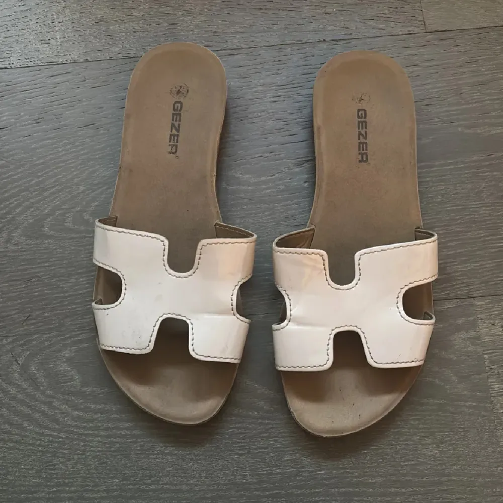 Snygga rosa sandaler från Gezer med öppen tå och ett stilrent designmönster på sulan. Perfekta för varma sommardagar. Sandalerna har en bred rem över foten som ger en bekväm passform.. Kengät.