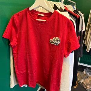 Röd t-shirt från Moncler - Snygg röd t-shirt från Moncler med ett broderat märke på bröstet. Perfekt för en casual look med sin kortärmade design. Tillverkad i mjukt material för extra komfort.