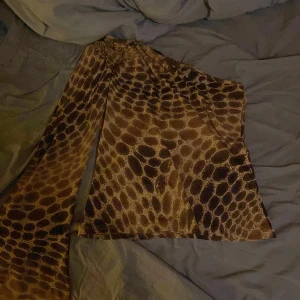 Mönstrad topp från Mavroudis - Säljer en unik topp från Mavroudis med ett djurinspirerat mönster i bruna och beige toner. Toppen har långa ärmar och en lös passform, perfekt för en trendig look.