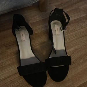 Klackskor - Medelhöga svarta klackar från Nelly. De är i sammeltsmaterial och har band runt fötterna. Använda en gång. 100 kr