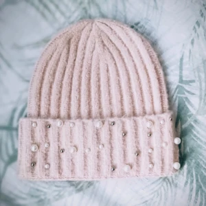 Beige ribbad mössa med pärlor - Snygg beige mössa med ribbad design och dekorativa pärlor. Perfekt för att hålla sig varm och stilren under kyliga dagar.