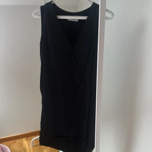 Svart klänning från Wera Stockholm - Elegant svart klänning från Wera Stockholm i en stilren design. Klänningen är ärmlös med en v-ringad hals och har en klassisk passform. Perfekt för en stilfull look.