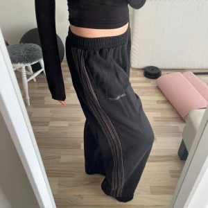 Svarta mjukisbyxor med ränder - Säljer ett par svarta Iets Frans byxor från Urban  Outfitters som aldrig har används då jag tycker de är lite för korta (jag är 176) de har randiga detaljer längs sidorna och lappen sitter kvar. Byxorna är oversize vilket är perfekt både till dans och mys. 