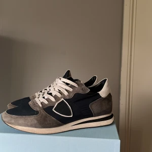 Philippe model skor  - Snygga sneakers i grått och blått med vita snören och detaljer i mocka. Skorna har en stilren design med en vit sula och är perfekta för en avslappnad stil. Nypris: 3000kr                   Blåa snöre, skopåse och box ingår.                           Pris kan diskuteras 