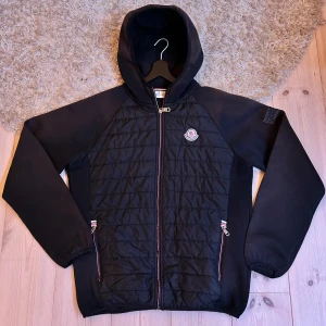 Moncler Cardigan  - Säljer en svart Cardigan från Moncler🔥 Den har en dragkedja framtill och två fickor med dragkedjor. 😍Den är quiltad på framsidan och har Moncler-loggan på bröstet. Perfekt för lite kyligare vår dagar🔥 strlk M men passar S, bra skick 7/10