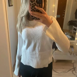 Vit stickad tröja - Säljer en stilren vit stickad tröja med långa ärmar och ribbade detaljer vid ärmslut och nederkant. Perfekt för en mysig och avslappnad look. Passar bra till både jeans och kjol.