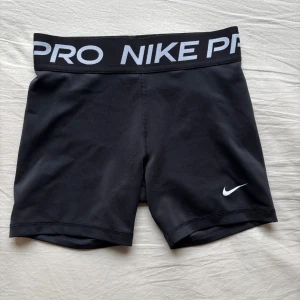 Svarta träningsshorts från Nike pro  - Snygga svarta träningsshorts från Nike med elastisk midja och vit logga. Perfekta för gymmet eller löprundan. De har en tight passform och är gjorda i ett bekvämt syntetmaterial som andas. storlek L i barn, Passar XS i dam💞. 