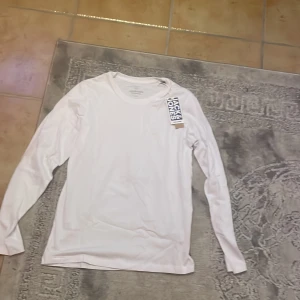 Vit långärmad tröja från Jack & Jones - Säljer en stilren vit långärmad tröja från Jack & Jones. Perfekt för en enkel och klassisk look. Tröjan är gjord i mjukt material och har en rund halsringning. Passar bra till både jeans och chinos. Helt ny har ej använt den.