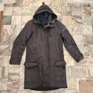 Grå G-Star jacka - Säljer en grå jacka från G-Star med huva och dragkedja. Jackan har flera fickor med knappar och en stilren design. Perfekt för kyligare dagar.