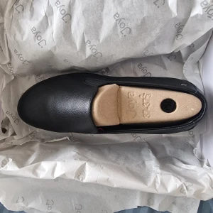 Svarta läderskor från Joya - Säljer ett par svarta läderskor från Joya i storlek 37. Skorna har en bekväm innersula och en slitstark yttersula. Perfekta för dig som söker komfort och stil i vardagen.