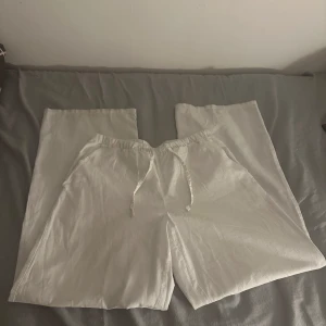 Vita linnebyxor från Gina Tricot - Snygga vita linnebyxor från Gina Tricot med en avslappnad passform. Byxorna har en elastisk midja med snörning för extra komfort. Perfekta för en somrig look!