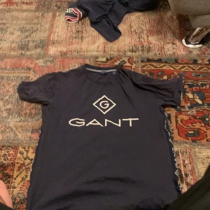 Mörkblå t-shirt från Gant - Snygg mörkblå t-shirt från Gant med stort logotryck på framsidan. Den har korta ärmar och en klassisk rund halsringning. Perfekt för en avslappnad stil.