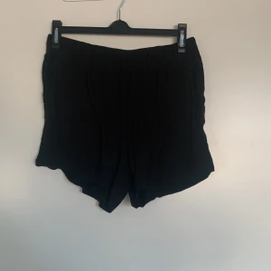 Svarta shorts från Visual Clothing Project - Snygga svarta shorts från Visual Clothing Project. De har en elastisk midja för extra komfort och en avslappnad passform. Perfekta för en stilren look.