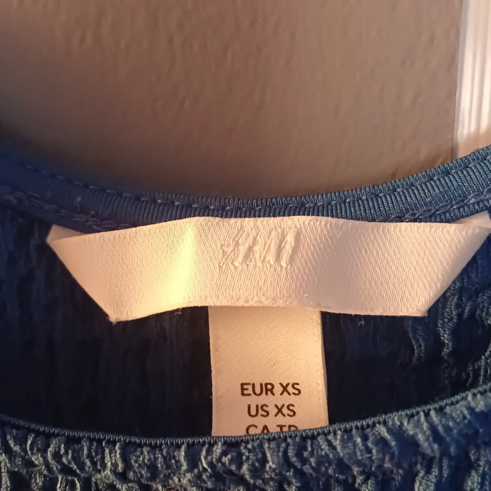 Snygg blå långklänning från H&M med smala axelband. Perfekt för varma dagar med sin lätta och luftiga design. Klänningen har en enkel och stilren look som gör den lätt att matcha med olika accessoarer.. Mekot.