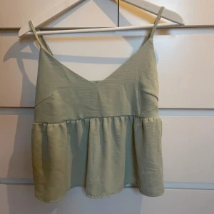 Ljusgrön volangtopp - Mint-/ljusgrön topp med smala justerbara axelband och volangdetaljer. Använd fåtal gånger så väldigt bra skick!