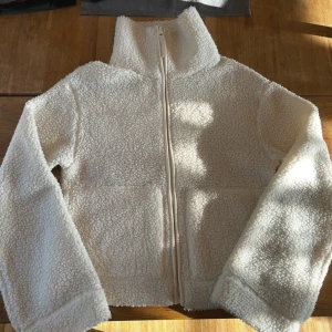 Vit teddyjacka med dragkedja - Mysig vit teddyjacka från Hm i storlek S. Jackan har en dragkedja framtill och långa ärmar. Perfekt för våren. Helt slutsåld!