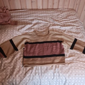 Beige och rosa tröja från Jacqueline de Yong - Säljer en snygg tröja från Jacqueline de Yong i beige och rosa med svarta ränder. Tröjan har en normal passform och trekvartsärmar, perfekt för en avslappnad stil. Sparsamt använd, bra skick. Passar mig bra som har strl S-M. Orginalpris ca 300kr
