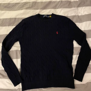 Mörkblå kabelstickad tröjan Ralph lauren - Säljer en riktigt snygg mörkblå kabelstickad tröja från Ralph lauren. Oanvänd med tags kvar. Är L men passar som en M. Nypris 2100kr