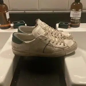 Säljer ett par vita sneakers från Philippe Model i bra skick. De har gröna detaljer och snörning. Skorna har lite slitage på tån och sulan, men är fortfarande snygga och bekväma. Perfekta för vardagsbruk!