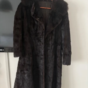 Mörkbrun pälsjacka - Säljer en elegant mörkbrun pälsjacka i mycket bra skick. Jackan har en klassisk långärmad design och är perfekt för kalla vinterdagar. Den är supermjuk och ger en lyxig känsla. Perfekt för att hålla sig varm och stilren under vintern! I mink, köpt på Vestiaire från Slovakien. 