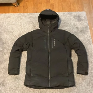 Svart vinterjacka från sail racing - Säljer en svart vinterjacka från Sail Racing i mycket bra skick. Jackan har en stilren design med dragkedja och huva, perfekt för kalla dagar. och har flera praktiska fickor. Passar både till vardags och utomhusaktiviteter. Grymt skön och varm. Jag säljer jackan eftersom jag växt ur den.