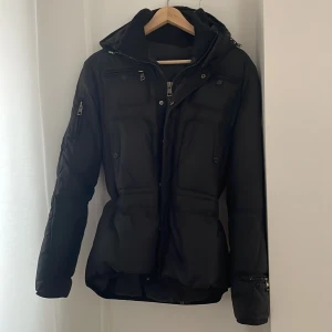 Svart vinterjacka  - Säljer en snygg svart vinterjacka  i mycket bra skick då den aldrig används. Jackan är välgjord med ganska mycket tyngd i sig då den är väldigt tjock, har en dragkedja framtill och fickor med knappar  och en praktisk huva. Perfekt för kalla vinterdagar! 🖤 