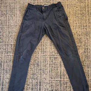 Mörkblå byxor från HARTON REPUBLIC - Säljer ett par mörkblå byxor från HARTON REPUBLIC i bra skick. De har en normal passform med knappar och dragkedja framtill. Perfekta för både vardag och lite mer uppklädda tillfällen. Materialet känns som bomull, vilket gör dem bekväma att bära hela dagen.