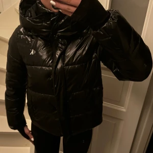 Svart pufferjacka från Calvin Klein Jeans - Säljer en snygg svart pufferjacka från Calvin Klein Jeans i storlek S. Jackan har en glansig finish och är perfekt för kyliga dagar. Den har en dragkedja framtill och långa ärmar. Perfekt för både höst och vinter!
