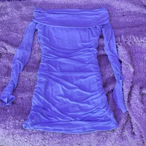Ljuslila offshoulder klänning - Säljer en superfin ljuslila offshoulder klänning i tight passform. Perfekt för fest eller en utekväll! Klänningen är i ett mjukt och stretchigt material som sitter bekvämt. Den har långa ärmar och en stilren design som verkligen sticker ut. Passar perfekt för vår och sommar.
