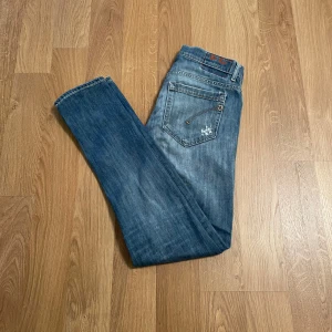 Dondup George - Säljer ett par snygga blå jeans i bra skick med coola slitningar på framsidan. De har en klassisk femficksdesign. Perfekta för en avslappnad stil och funkar året runt. Passar både till vardags och fest! Stl W 31